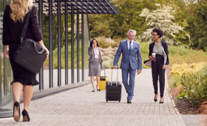 Group Of Business Delegates With Luggage Arriving At Conference Hotel