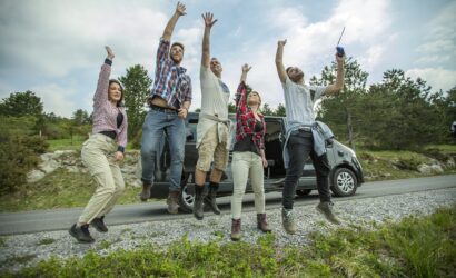 Group of young cheerful friends jumping having fun outdoors on the road